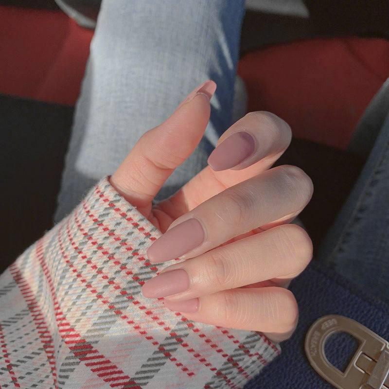 Wearable false nails in a soft pink-mauve shade, featuring long almond-shaped tips with a glossy finish