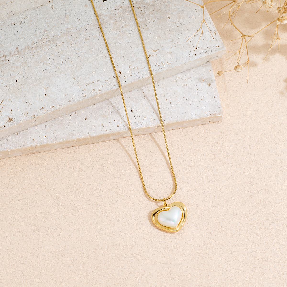 Heart-shaped pendant necklace in Stainless Steel with a gold-tone finish and pearly white center detail.