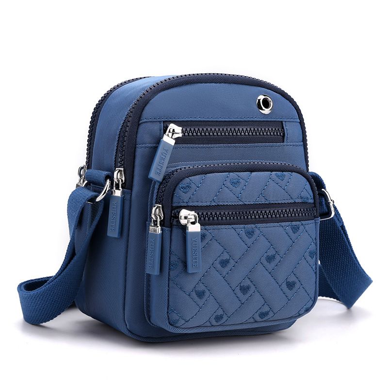 Crossbody bag in Solid Color navy blue nylon, featuring quilted texture, multiple zip pockets, and adjustable strap