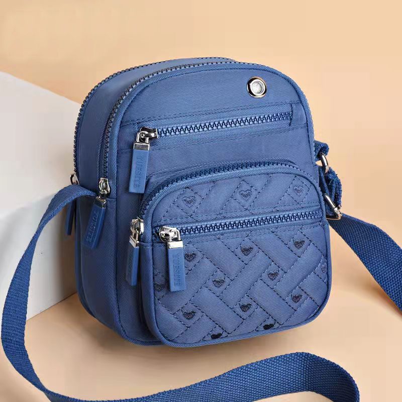 Crossbody bag in Solid Color blue nylon, featuring quilted geometric stitching, multiple zip pockets and adjustable strap