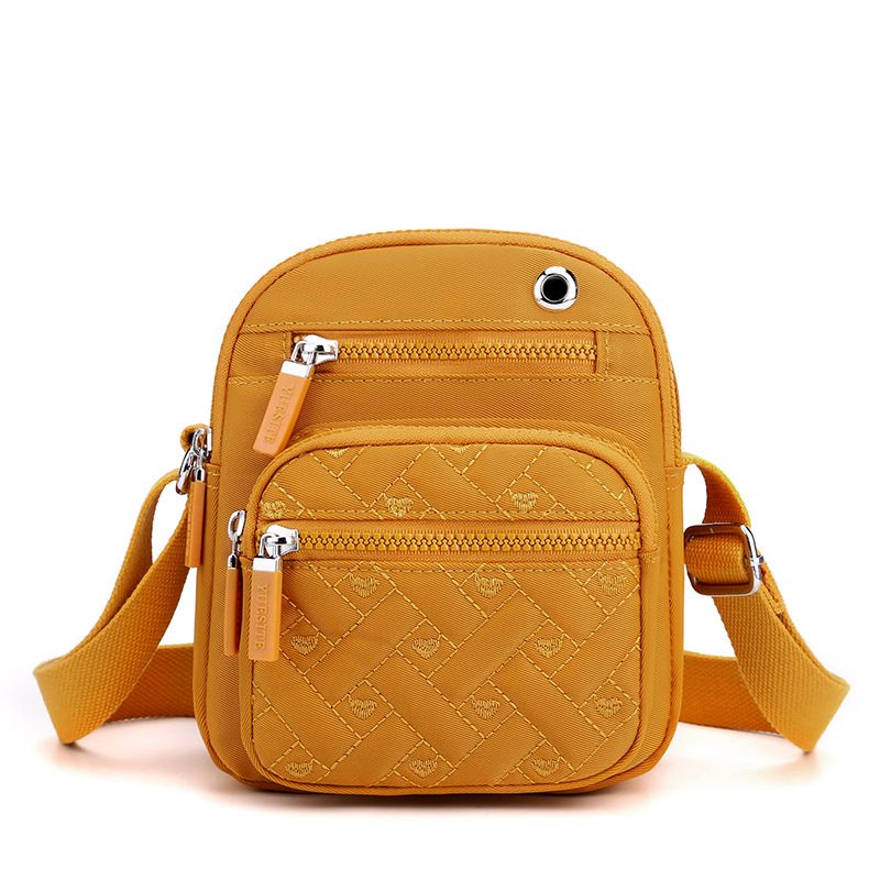 Crossbody bag in Solid Color mustard yellow nylon, featuring quilted texture, multiple zip pockets and adjustable strap