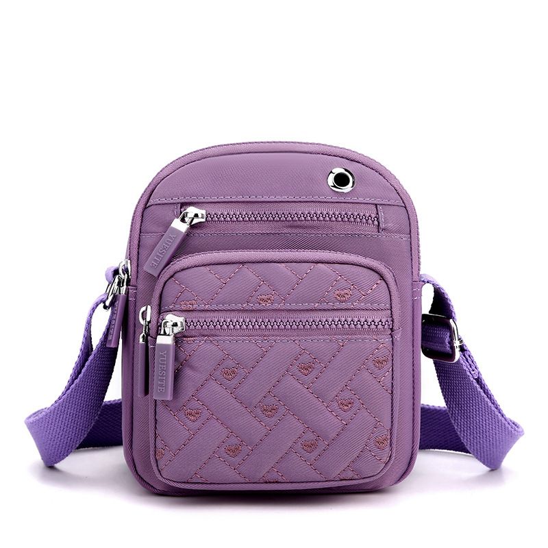 Crossbody bag in Solid Color purple nylon canvas with quilted geometric stitching, dual zippers and adjustable strap